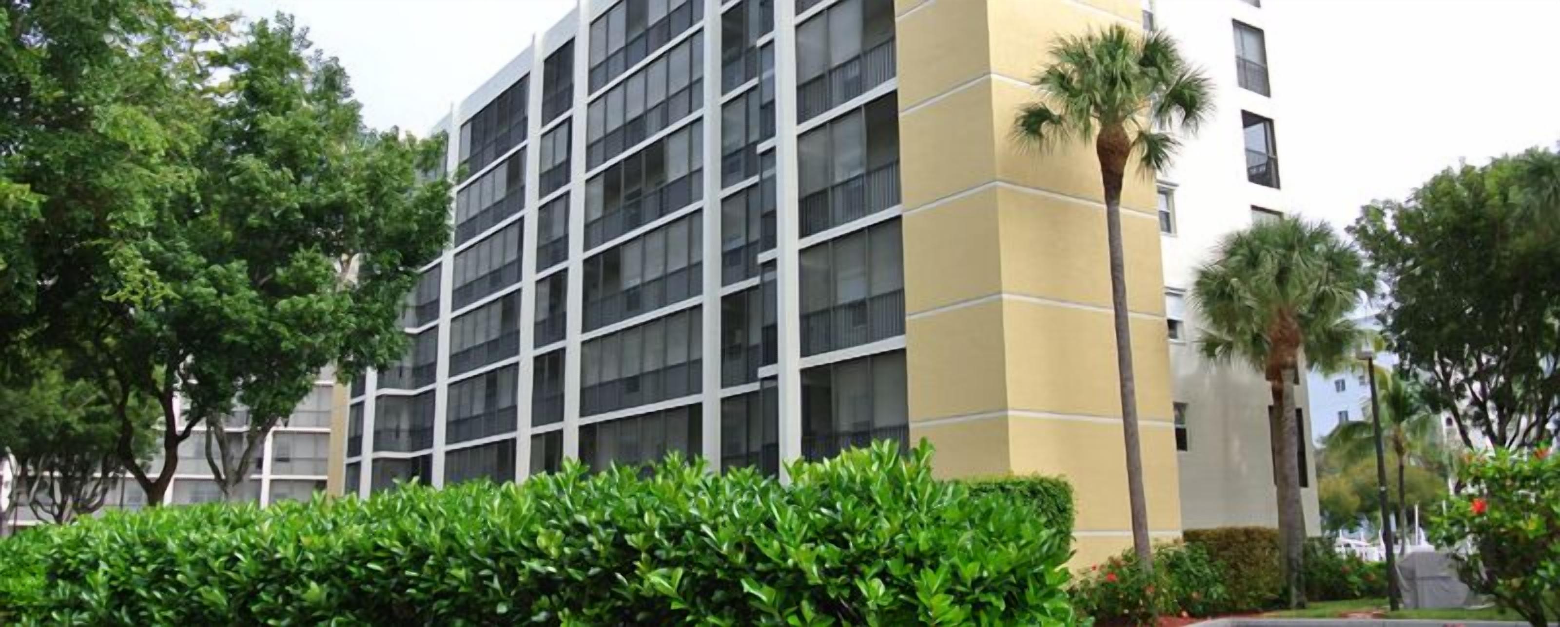 A multi-story building with a modern architectural design, featuring a grid of windows and a yellow facade.