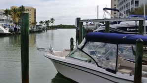 A marina with boats docked, a building with a white facade, and palm trees in the background. - 2BR – Penthouse, Pool, Beach & Water Views (Fort Myers Beach)