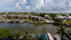 A marina with boats docked, a swimming pool, and buildings with a uniform architectural style. - 2BR – Penthouse, Pool, Beach & Water Views (Fort Myers Beach)