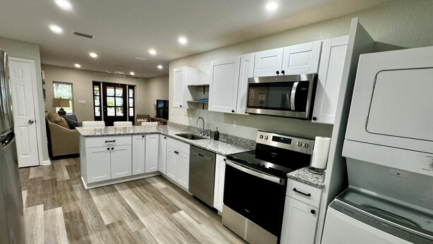 A modern kitchen with white cabinetry, stainless steel appliances, and a herringbone wood floor. - Charming 2-bedroom cottage with full kitchen and WiFi in Pensacola. Sleeps 4. (Pensacola)