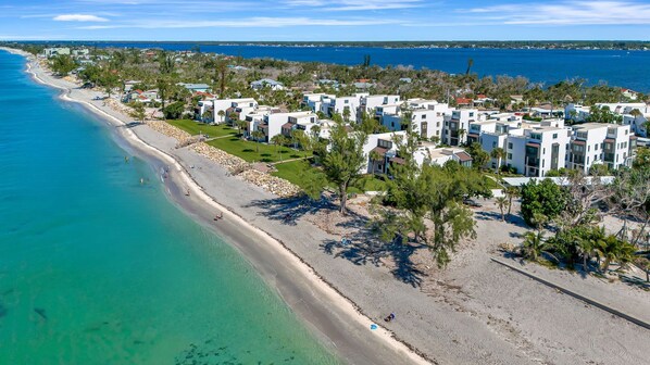 A coastal resort with beachfront villas, a sandy beach, and clear blue waters.