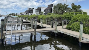 A waterfront property with a dock, a small bridge, and modern buildings with balconies. - Open Deck – 2BR Loft Condo with Bay Views (Englewood)