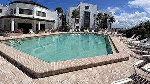 A modern hotel with a swimming pool, lounge chairs, and palm trees. - Open Deck – 2BR Loft Condo with Bay Views (Englewood)