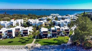 A coastal residential area with modern white buildings, a clear blue sky, and a view of the sea.