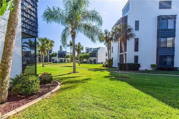 A modern hotel courtyard with palm trees, well-maintained grass, and contemporary buildings. - Effortless Escape – Walk-Out 2BR at Tamarind (Englewood)