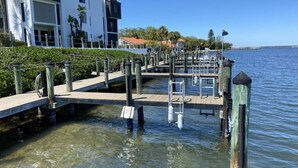 A marina with docked boats, a wooden walkway, and a modern building with balconies. - Effortless Escape – Walk-Out 2BR at Tamarind (Englewood)