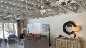 A spacious living room with a grey sofa, a wooden cabinet, and a dining area with a table and chairs.