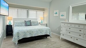 A bedroom with a bed, nightstands, a dresser, and a large mirror. - Modern Comfort – 2BR Bayside Condo at Tamarind (Englewood)