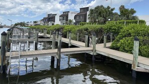 A waterfront property with a dock, a small bridge, and modern buildings with balconies. - Modern Comfort – 2BR Bayside Condo at Tamarind (Englewood)