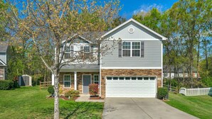 A two-story house with a garage, a front porch, and a well-maintained lawn.