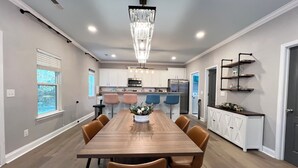 A modern kitchen with white cabinets, stainless steel appliances, and a dining area with a wooden table and chairs.