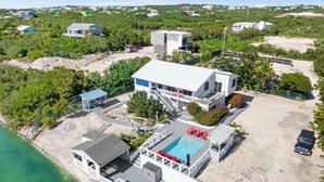 An aerial view of a coastal property with a swimming pool, a covered patio, and a dock. - Waterfront 5BR Home w/ Pool, Gated Parking & Prime Location! (Cooper Jack Bay Settlement)