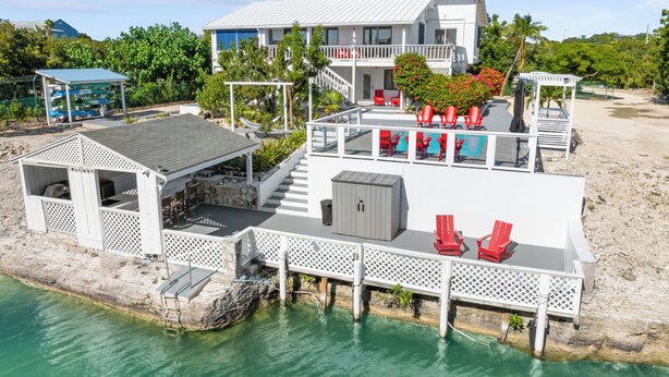 A waterfront property with a covered deck, outdoor seating, and a pool area. - Waterfront 5BR Home w/ Pool, Gated Parking & Prime Location! (Cooper Jack Bay Settlement)