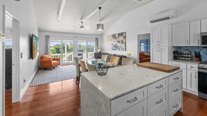 A spacious kitchen with white cabinetry, a marble island, and a dining area with a view. - Waterfront 5BR Home w/ Pool, Gated Parking & Prime Location! (Cooper Jack Bay Settlement)