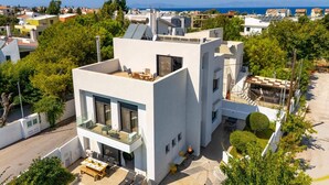 Un bâtiment moderne doté d’une terrasse sur le toit, d’un balcon en verre et offrant une vue sur la mer.