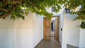 Un couloir étroit aux murs blancs, avec une porte en bois donnant sur un hall.