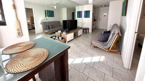 Una sala de estar moderna con un espejo grande, televisor, sofá y sillón.