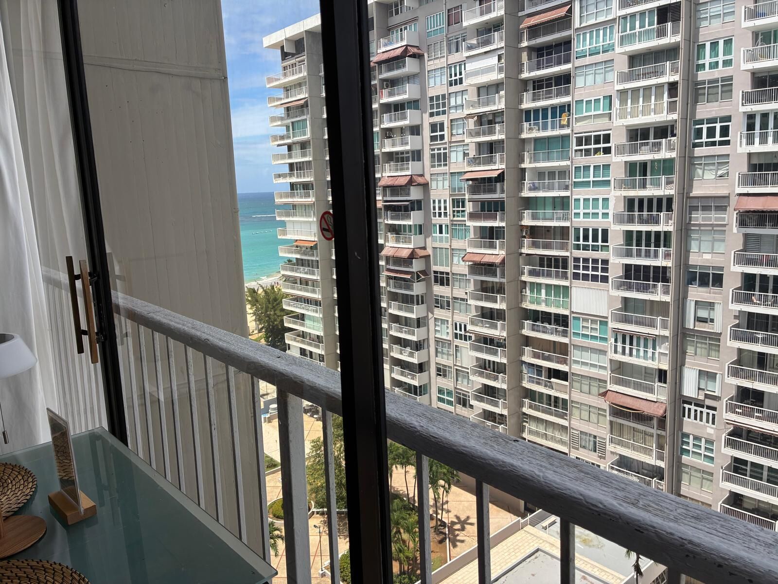 A high-rise building with multiple balconies, a view of the ocean, and a clear sky.