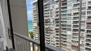 Un edificio de gran altura con varios balcones, vista al océano y cielo despejado.