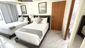 Une chambre d’hôtel avec deux lits, une porte en bois, un sol en marbre et des œuvres d’art accrochées aux murs.