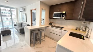 Une cuisine moderne  équipée d’un four à micro-ondes encastré, d’un évier et d’un coin bar.