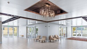 A spacious lobby with a high ceiling, a chandelier, and a seating area with chairs. - 2BR/2BA Luxury Bywater Condo In New Orleans! (New Orleans)