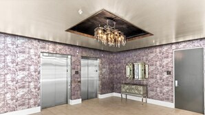 A spacious lobby with three elevators, a decorative chandelier, and a mirrored console. - 2BR/2BA Luxury Bywater Condo In New Orleans! (New Orleans)