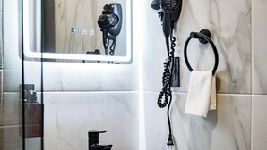Een moderne badkamer met een marmeren wand, een zwarte kraan, een haardroger en een handdoekhouder.