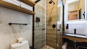 Een moderne badkamer met een douchecabine, toilet, wastafel met spiegel en een handdoekhouder.