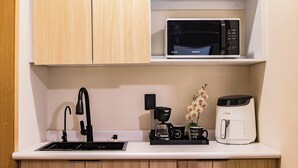 Une petite cuisine équipée d’un four à micro-ondes, d’une machine à café et d’un évier.