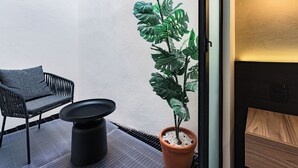 Una habitación moderna con una silla negra, una mesita redonda y una planta en maceta.