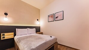 A modern bedroom with a bed, bedside tables, wall-mounted light, and two framed pictures. - Private suites in remodeled old house in Roma Norte (Mexico)