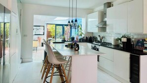 A modern kitchen with a central island, white cabinetry, and a view to the outside. - Townhouse by Notting Hill - Sleeps5/petsok/tv/wifi (London)