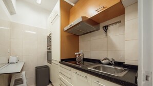 Eine Küche mit schwarzer Arbeitsplatte, Spüle aus Edelstahl und einem Mülleimer.