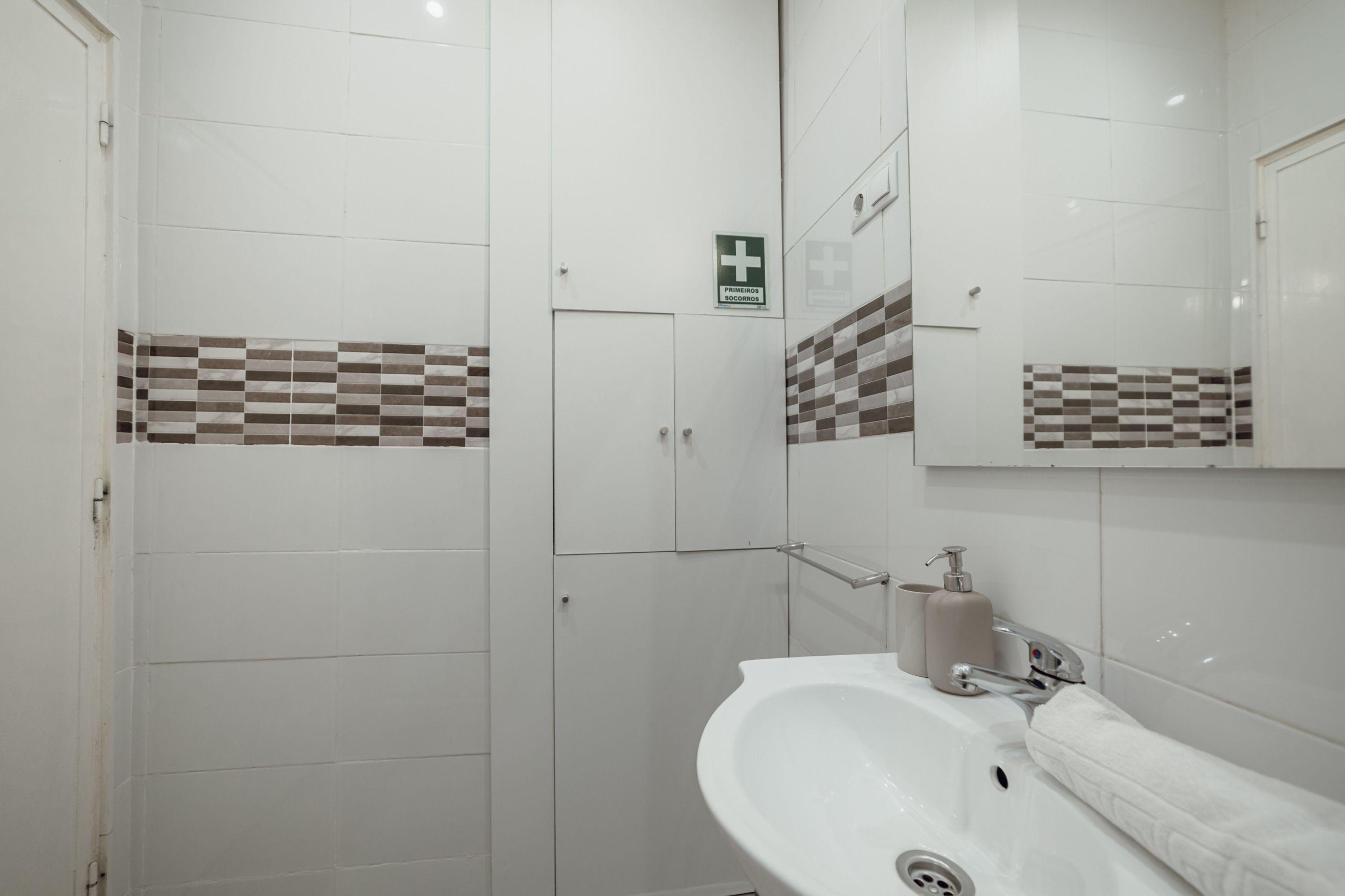 A modern bathroom with a white sink, a mirror, and a shower area.