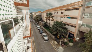Ein mehrstöckiges Gebäude mit einer gemusterten Fassade, eine Straße mit parkenden Autos und eine Palme.