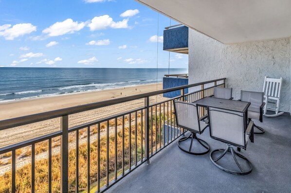 A balcony with a view of the beach and ocean.