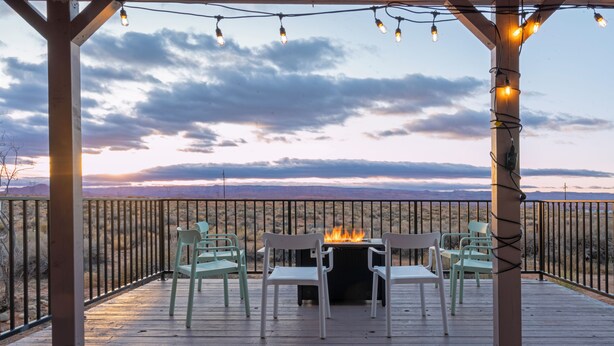 Una terrazza esterna con un elemento decorativo a forma di fuoco, circondata da sedie e vista sulle montagne.