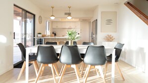 Una cucina moderna con mobili bianchi, un'isola centrale e un'area pranzo con sedie nere e un tavolo bianco.