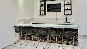 A modern kitchen with a marble countertop, black metal chairs, and a built-in TV. - ISIS HOTEL BOUTIQUE (Parras)