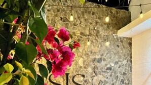 A stone wall with the word "SIS" and a seating area with cushions. - ISIS HOTEL BOUTIQUE (Parras)