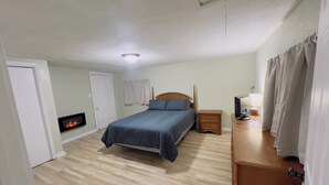 A bedroom with a bed, bedside table, lamp, and a fireplace.