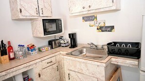 A compact kitchen with marble cabinets, a microwave, a sink, and various kitchen appliances. - Centrally Located Apartment – Dine, Explore, Relax (Rock Sound)
