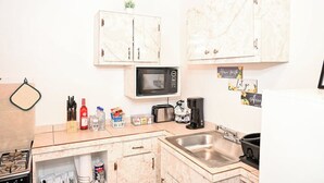 A compact kitchen with a microwave, toaster, sink, and cabinets. - Centrally Located Apartment – Dine, Explore, Relax (Rock Sound)