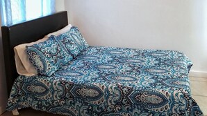 A bedroom with a bed, a ceiling fan, a window with curtains, and a wall with a small picture. - Centrally Located Apartment – Dine, Explore, Relax (Rock Sound)