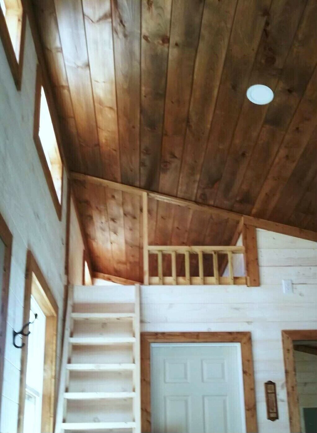 Interno in legno con una scala che conduce a un piano superiore, una porta bianca e una piccola finestra.