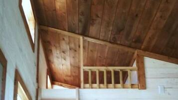 Interno in legno con una scala che conduce a un piano superiore, una porta bianca e una piccola finestra.