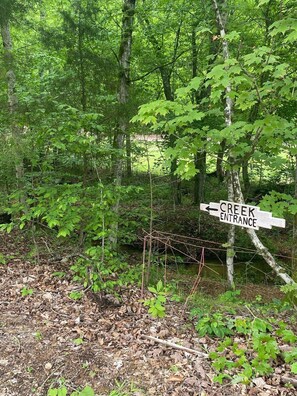 A signpost in a wooded area with a label pointing to 'CREEK ENTRANCE'.