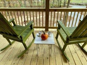 A wooden deck with two green rocking chairs and a small table with a pumpkin and two cups. - Secluded Creekside Cabin w/ Loft (Linden)