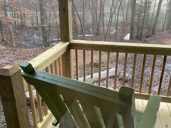 Eine Holzterrasse mit Geländer, die einen Blick auf eine bewaldete Landschaft bietet.